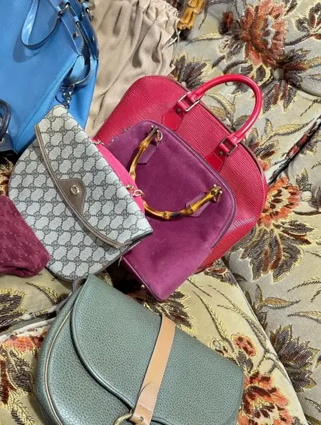 Vintage designervesker i skinn lagt utover et blomstret stoff.