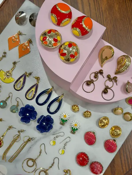 Vintage øredobber stilt opp på rosa utstillingsklosser i butikken.