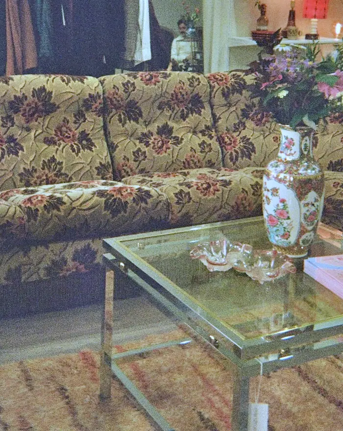 Sittegruppe i butikken med blomstret sofa, glassbord og en malt vase.